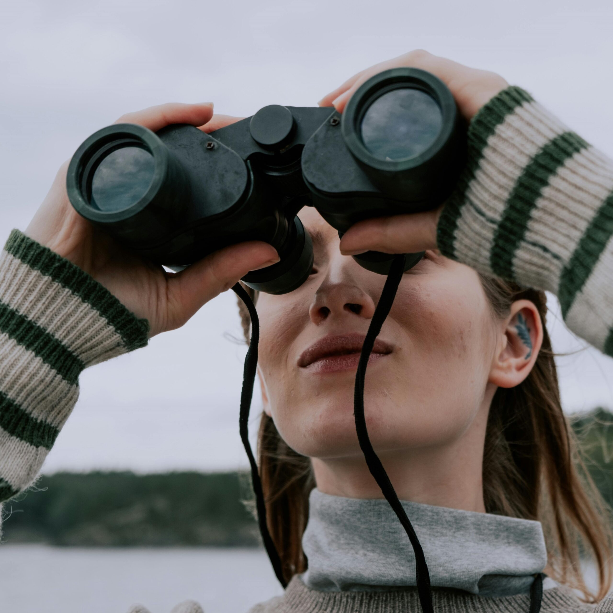 nainen katsoo kiikareilla yläviistoon